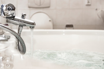 Water flows from a chrome mixer to a luxurious spa bath or whirlpool, with air bubbles to relax....