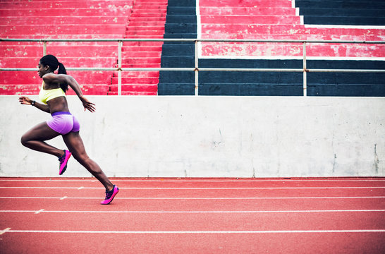 Young female sprinter running on track 