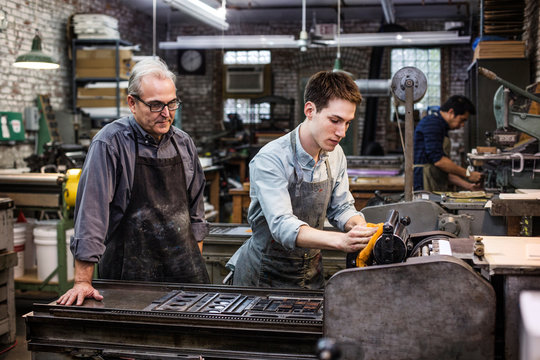 Worker and trainee by printing press 