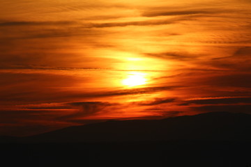 Mysterious looking cloudy sky at sunset over high mountains on warm sunny day