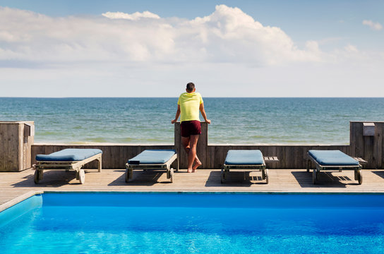 Rear view of man looking at ocean from beach resort