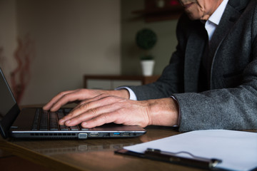 Hands of a mature elegant man using laptop