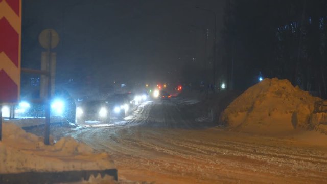 Cars passes at night along a snowy street in the city