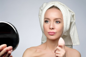 beautiful young woman using beauty sponge for applying foundation for make-up