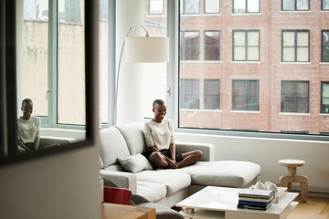 Young bald woman sitting on sofa in living room
