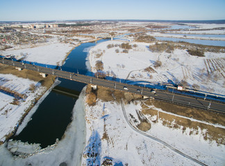 Photo from above with roads, building, lots, bridges, river on a winter day. Aerial city view with cars