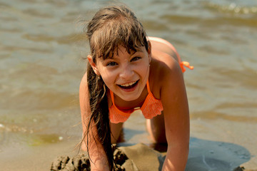 Teenage girl lying on the sandy beach on a hot summer day