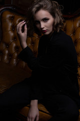 Fashionable brunette model with curly hair posing with contrast light