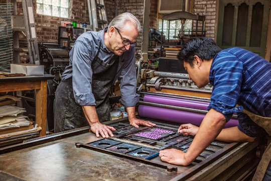 Two workers at printing press 