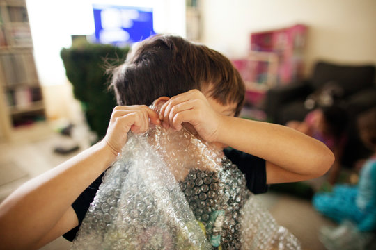 Boy (4-5) popping bubble wrap 