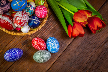 Easter eggs with tulips on weathered wooden background