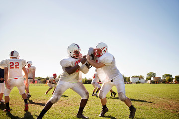 Teenage football team (14-15, 16-17) practicing tackle football 
