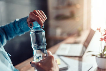 Woman opening bottle of water in the office