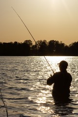 Silhouette of angler catching the fish during suny day