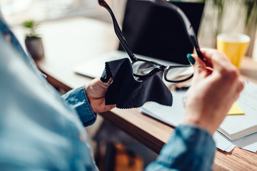 Woman cleaning eyeglasses at her office