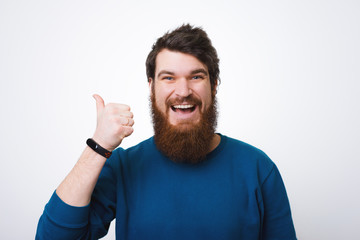 Handsome happy bearded young man smiling and thumbs up, guy wearing blue sweater isolated on white background