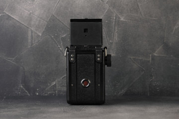 The old medium-format scaling film camera on grey cement background. TLR film camera.