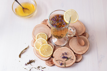 Top view of traditional Russian drink with honey, lemon and dried herbs in a glass cup on wooden table
