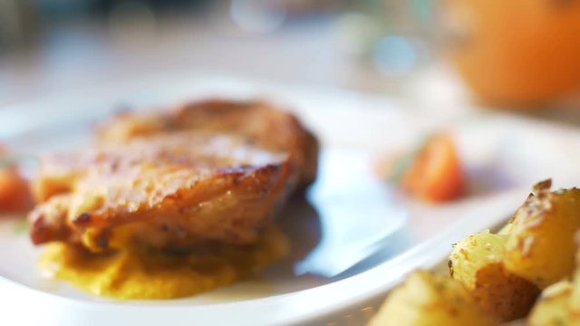 Nice chicken grill meat on white plate with sauce, poteto and tomato. Close up 4k food footage.
