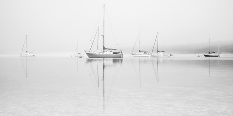 Sailing boats on misty lake