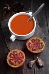 bowl of tomato sauce with split tomatoes and spices on rustic wood with natural light