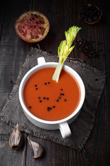 bowl of tomato sauce with celery branch and spices on rustic wood with natural light