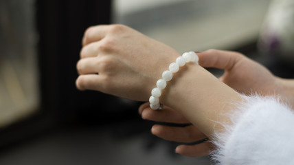 bracelet on hand, bracelet from pearls on hand, girl touches bracelet on hand (horizontally).