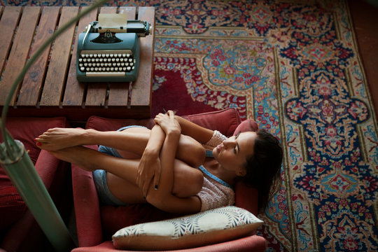 Young woman lying on armchair 