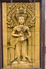 Fototapeta na wymiar An Apsara dancing carved on the sandstone wall background. Apsara is a female spirit of the clouds and waters in Hindu culture. Her figure prominently in the sculpture, dance, literature and painting.