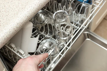 Man opened the dishwasher and was going to get perfectly clean dishes after washing.