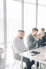 Businessman arguing with colleagues looking at him during meeting at conference room