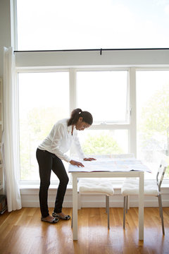 Woman studying blueprints in living room 