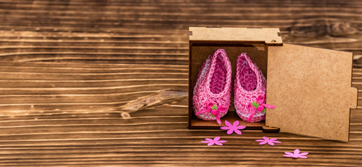 decoration with pink baby shoe, wooden background, space for text