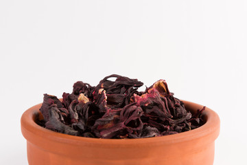 petals of dry hibiscus tea  in the clay pot isolated on white background