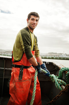Man tying a knot on fishing boat 