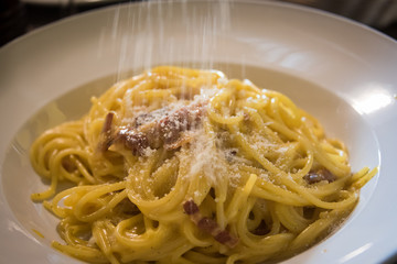 Hot Carbonare pasta with bacon and egg sauce is sprinkled with parmesan cheese.