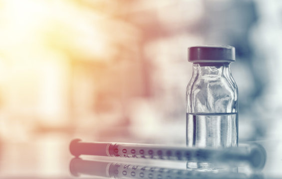 Closeup of medicine vial or flu, measles vaccine bottle with syringe and needle for immunization on vintage medical background, medicine and drug concept
