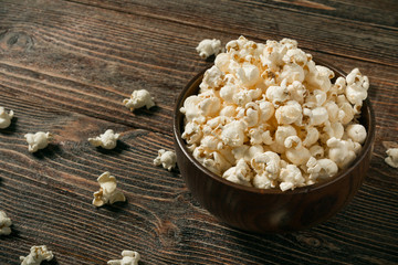 Popcorn in bowl on old wooden background.