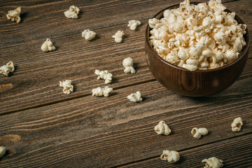 Popcorn in a bowl on wooden old boards.