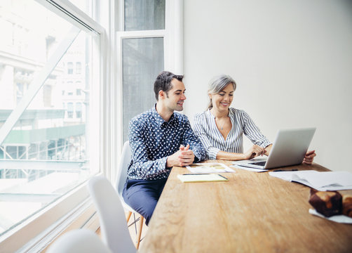 Man and woman using laptop at desk 