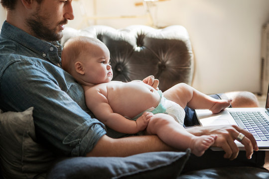 Man sitting on sofa with his baby girl (6-11 months) 
