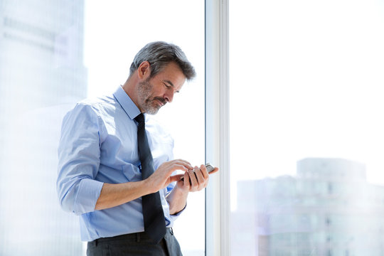 Business man smiling and texting on smartphone 