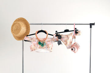 Unusual presentation of a swimsuit for buyers, fashion blog, glossy magazine, advertising, catalog. Stylish swimsuit in soft colors hanging on a hanger. A lot of accessories for a trip to luxury beach