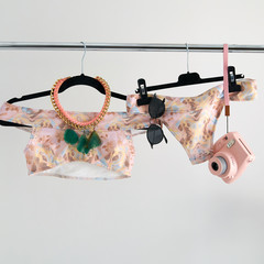 Unusual presentation of swimsuit for buyers, fashion blog, glossy magazine, advertising, catalog. Stylish swimsuit in soft colors hanging on a hanger. A lot of accessories for a trip to luxury beach.