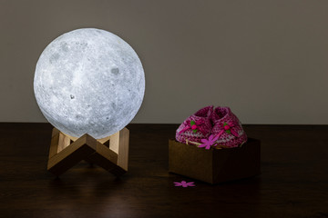 moon lamp and baby slipper on wooden table