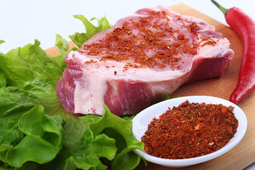 Fototapeta premium Raw pork steak with herbs, chili pepper and spices on cutting board. Ready for bbq.