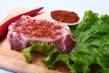 Raw pork steak with herbs, chili pepper and spices on cutting board. Ready for bbq.