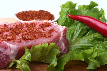 Raw pork steak with herbs, chili pepper and spices on cutting board. Ready for bbq.