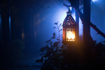 Beautiful colorful illuminated lamp in the garden in misty night. Retro style lantern at night outdoor.