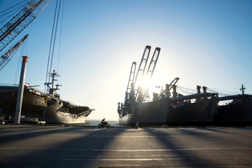 Man on motorcycle riding next to docked ships 